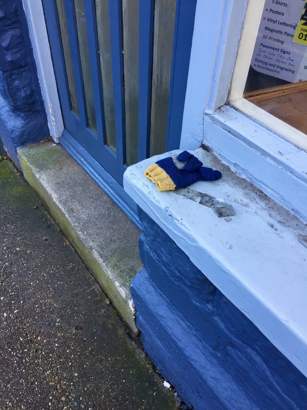  A lovely yellow and blue glove on a ledge outside a shop. 