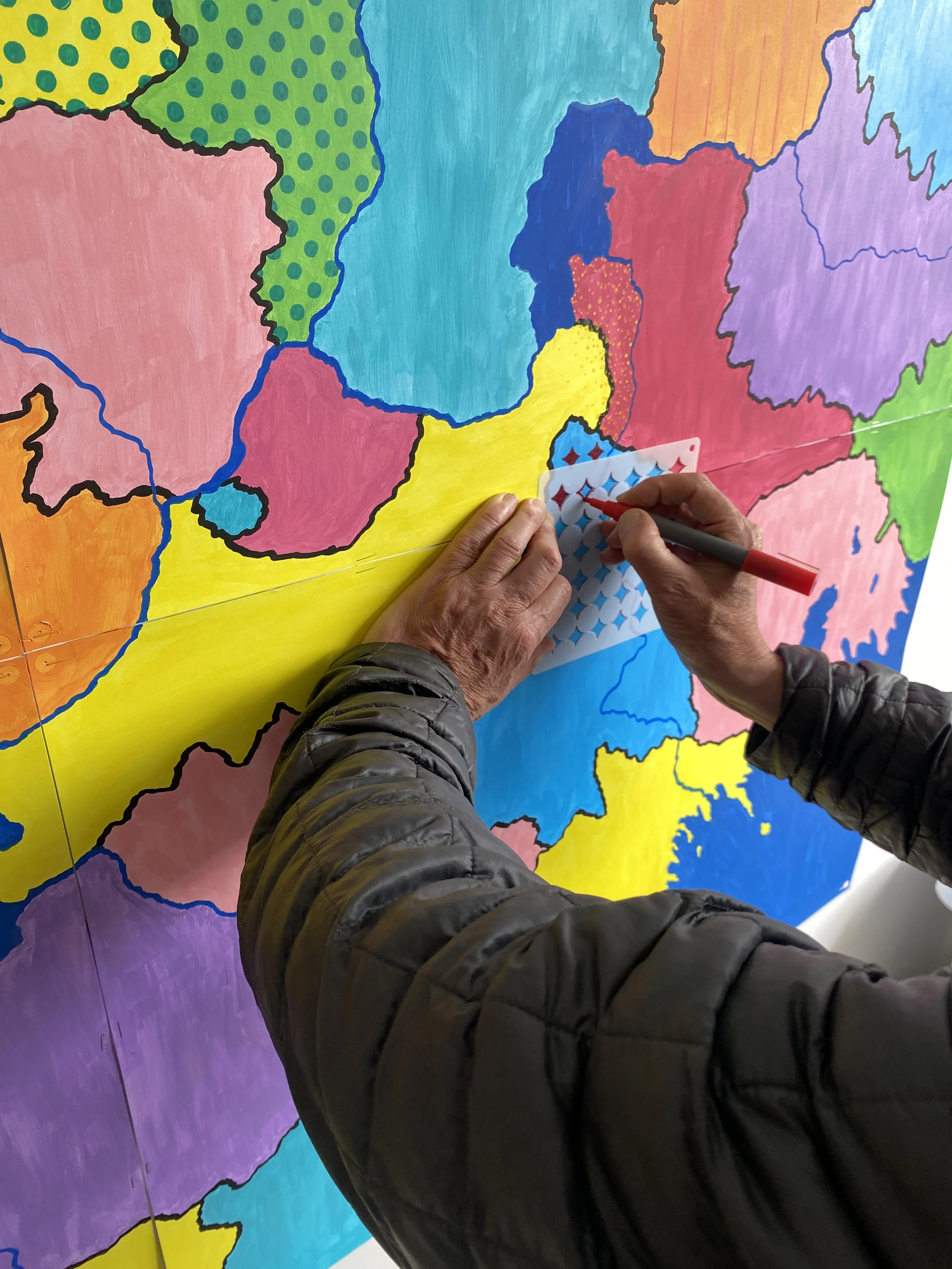  Another person uses a stencil to add a pattern to the map. 
