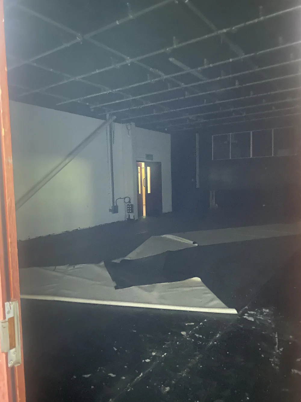  The dark room, with what looks like control booth windows, lots of rigging, and what might be a photography backdrop lying on the floor. 