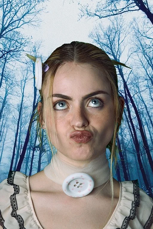 Portrait of a blonde woman against a dark background looking upward with a neutral expression, wearing a pearl necklace with a silver pendant and a white lace top. Fashion