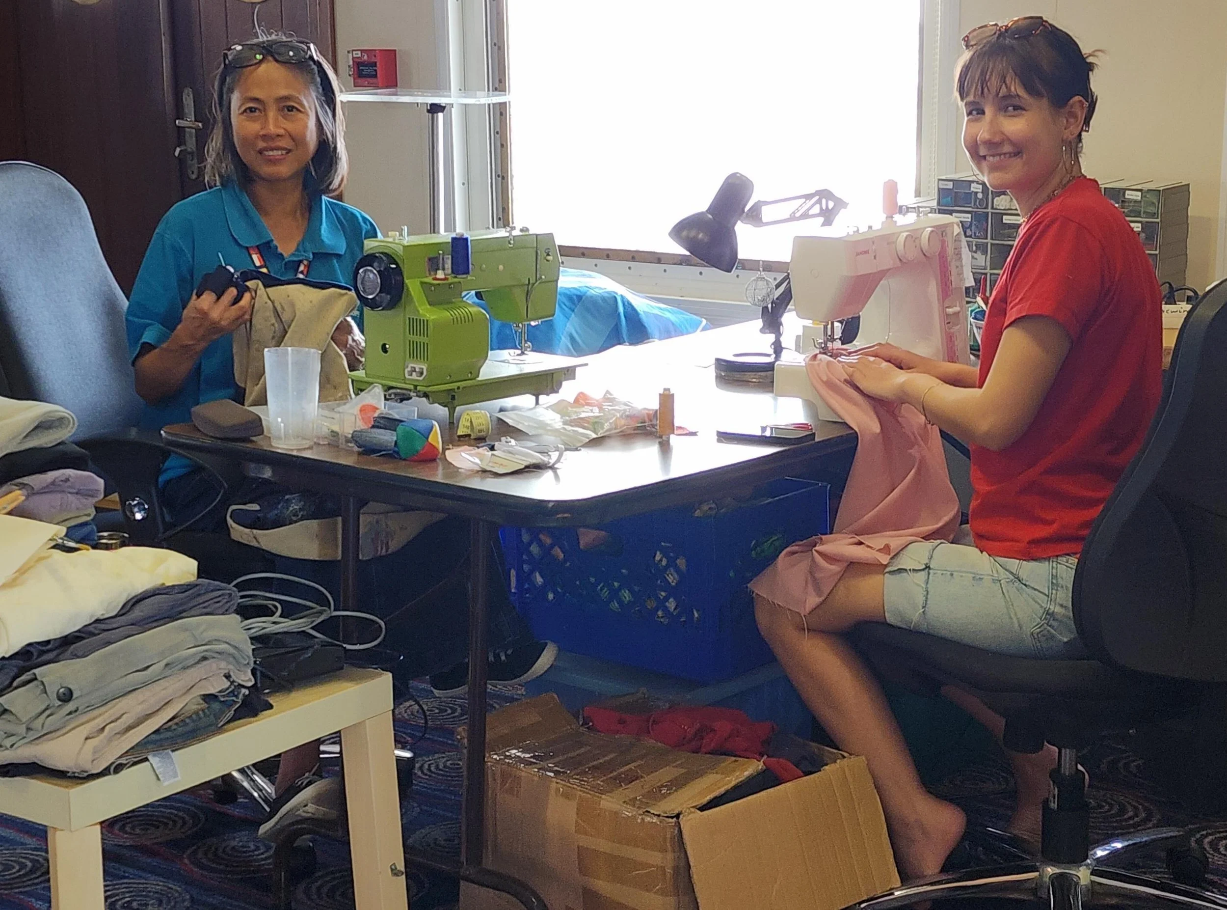 Malou repairing some of the ship workers' clothes with her Swiss friend, Gioia 