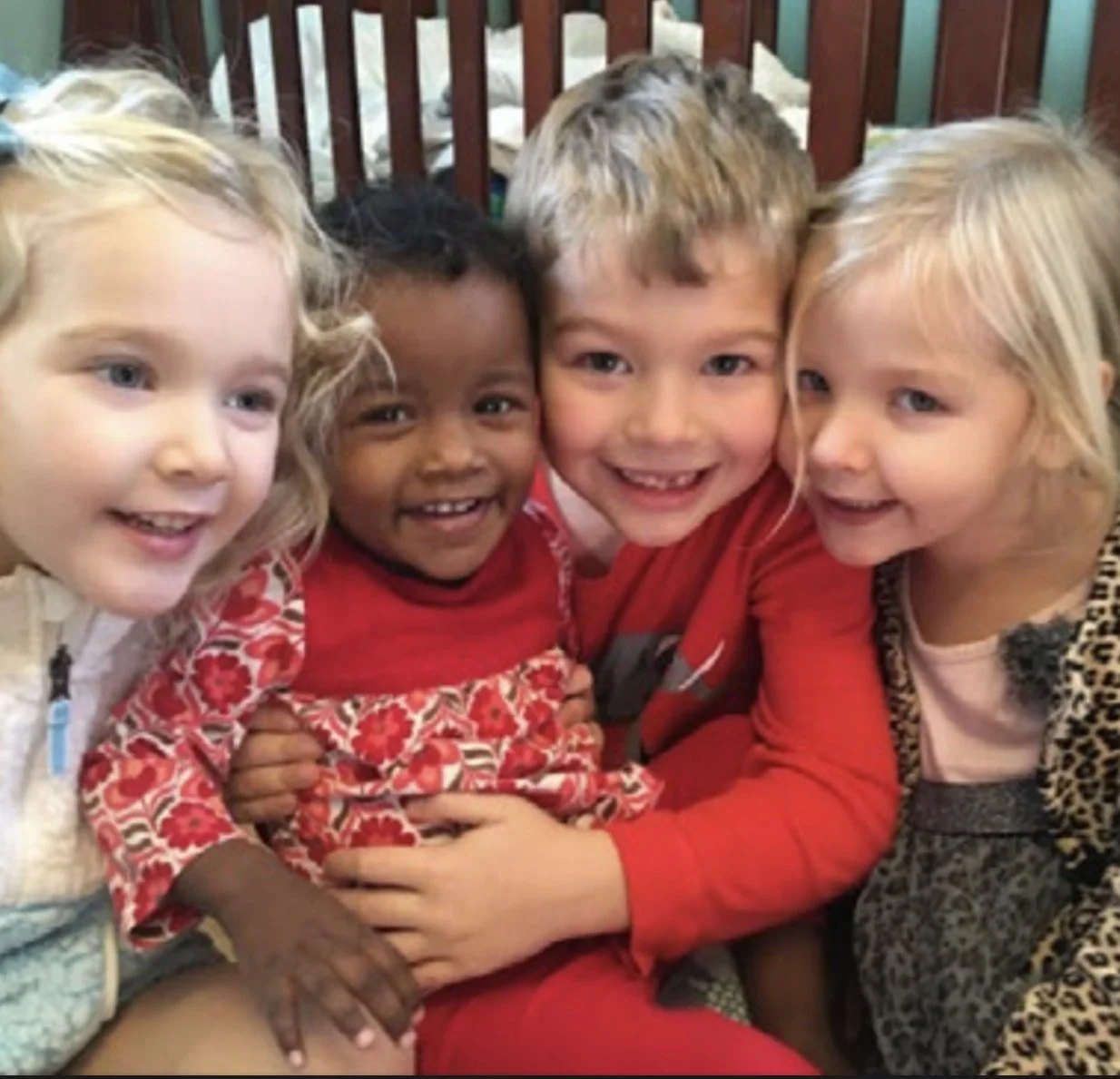 Four children smiling and hugging each other