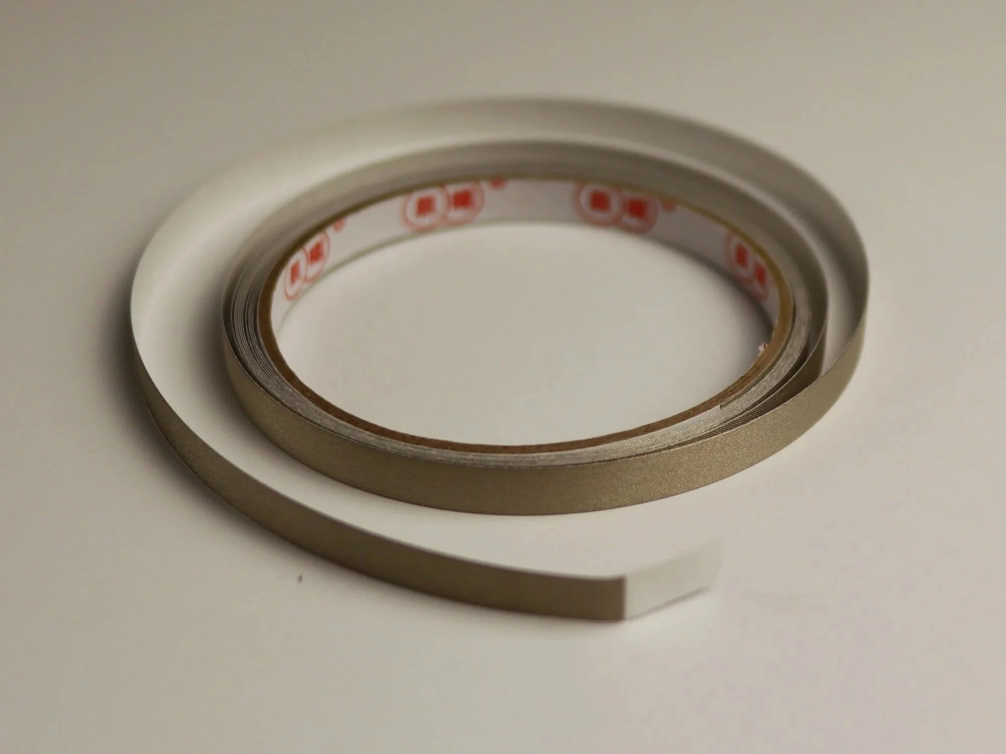 a roll of the gray conductive nylon fabric tape on the market lying on a white surface.