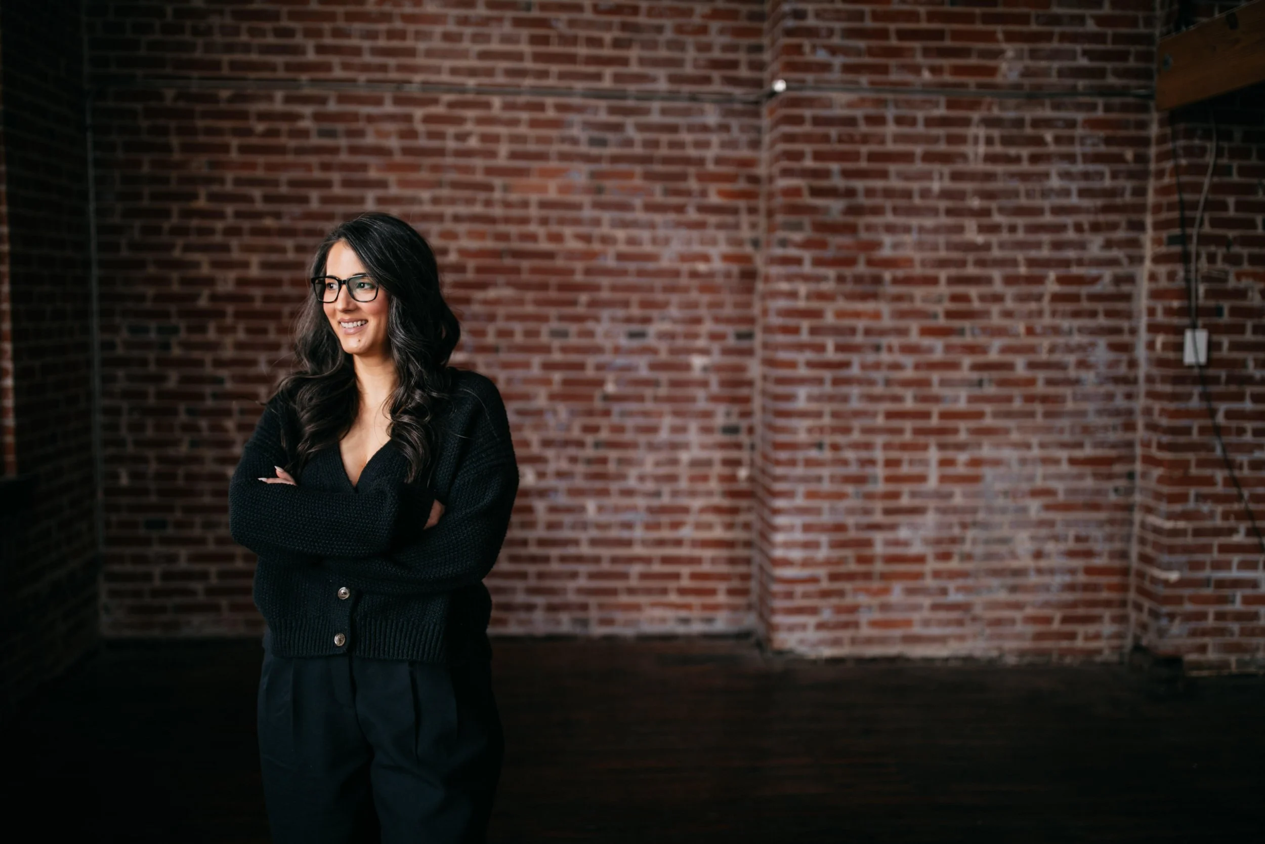 An image of Sara Farrell standing in front of an exposed brick wall