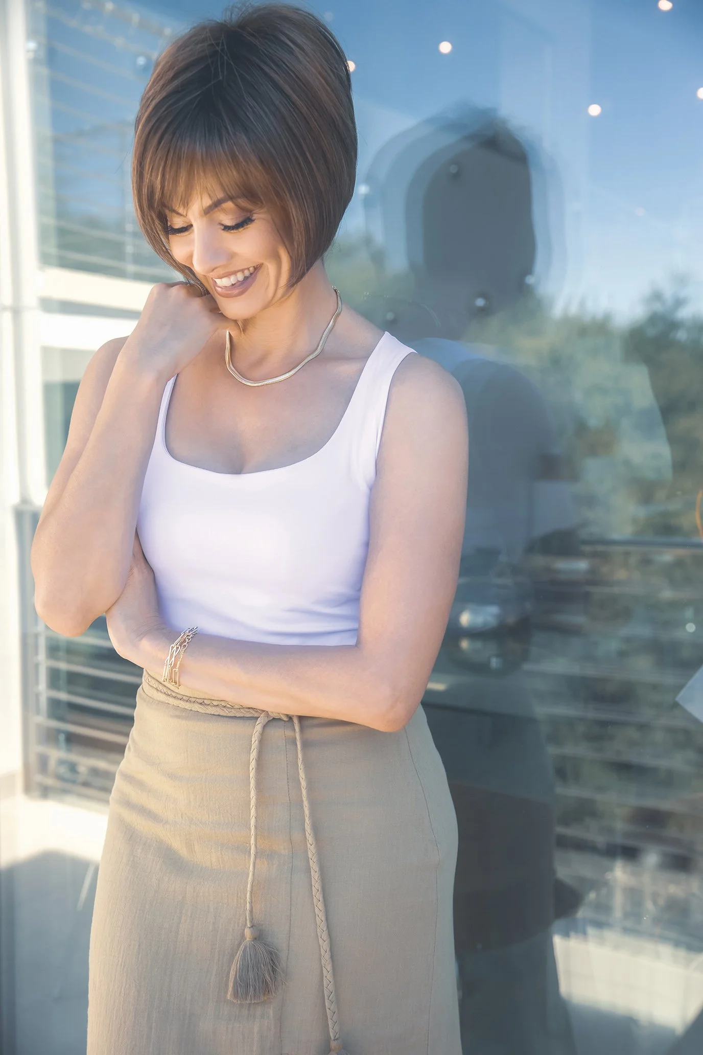 A woman smiling and looking down wearing the Meadow wig by Noriko