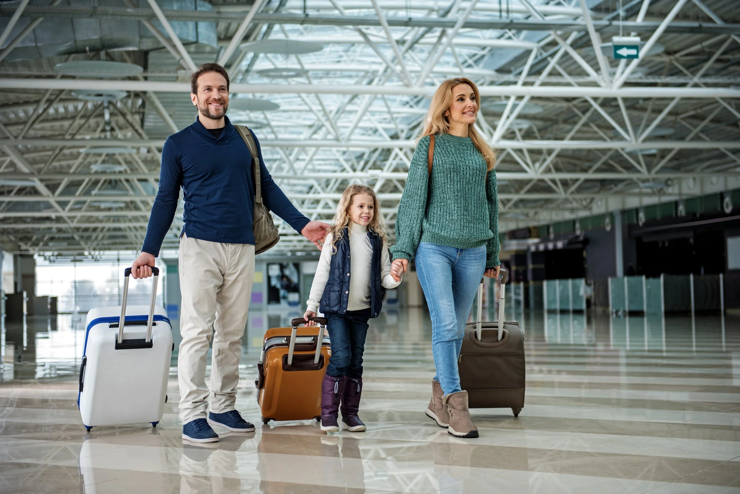 Family walking their suitcases through airport