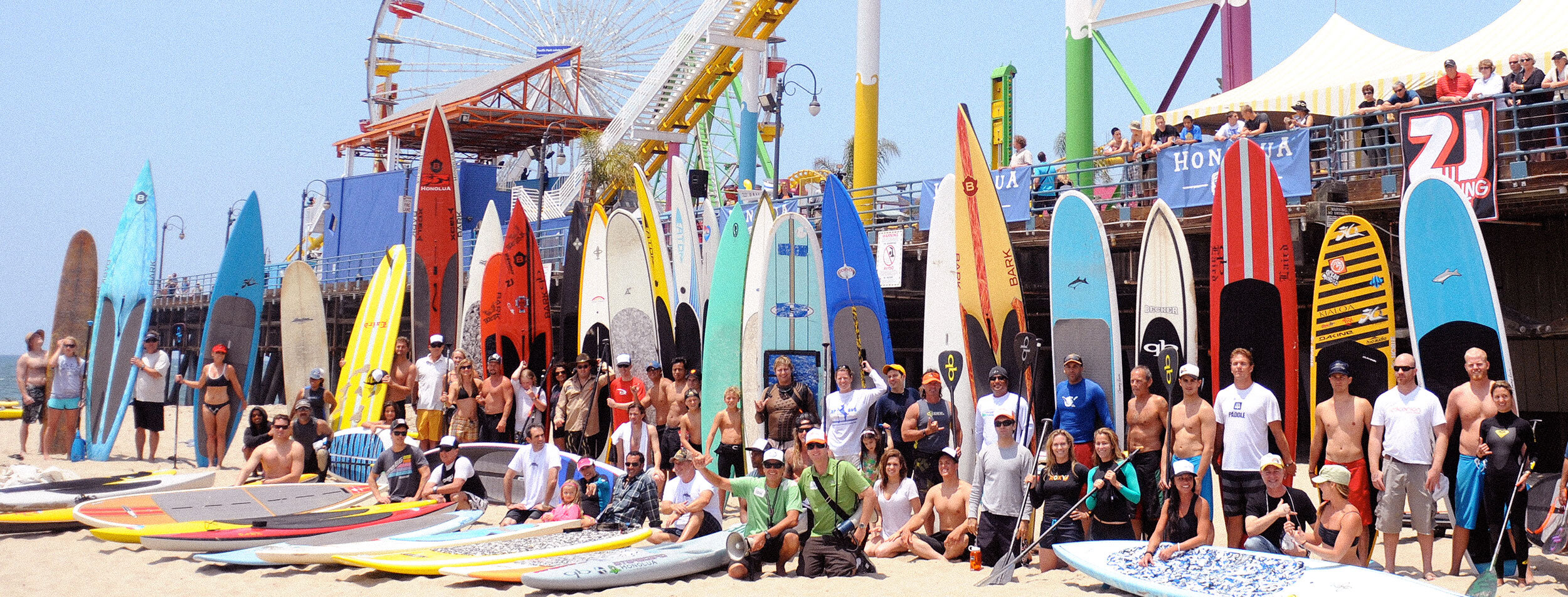 Group of people standing in front of Paddle Boards on beach