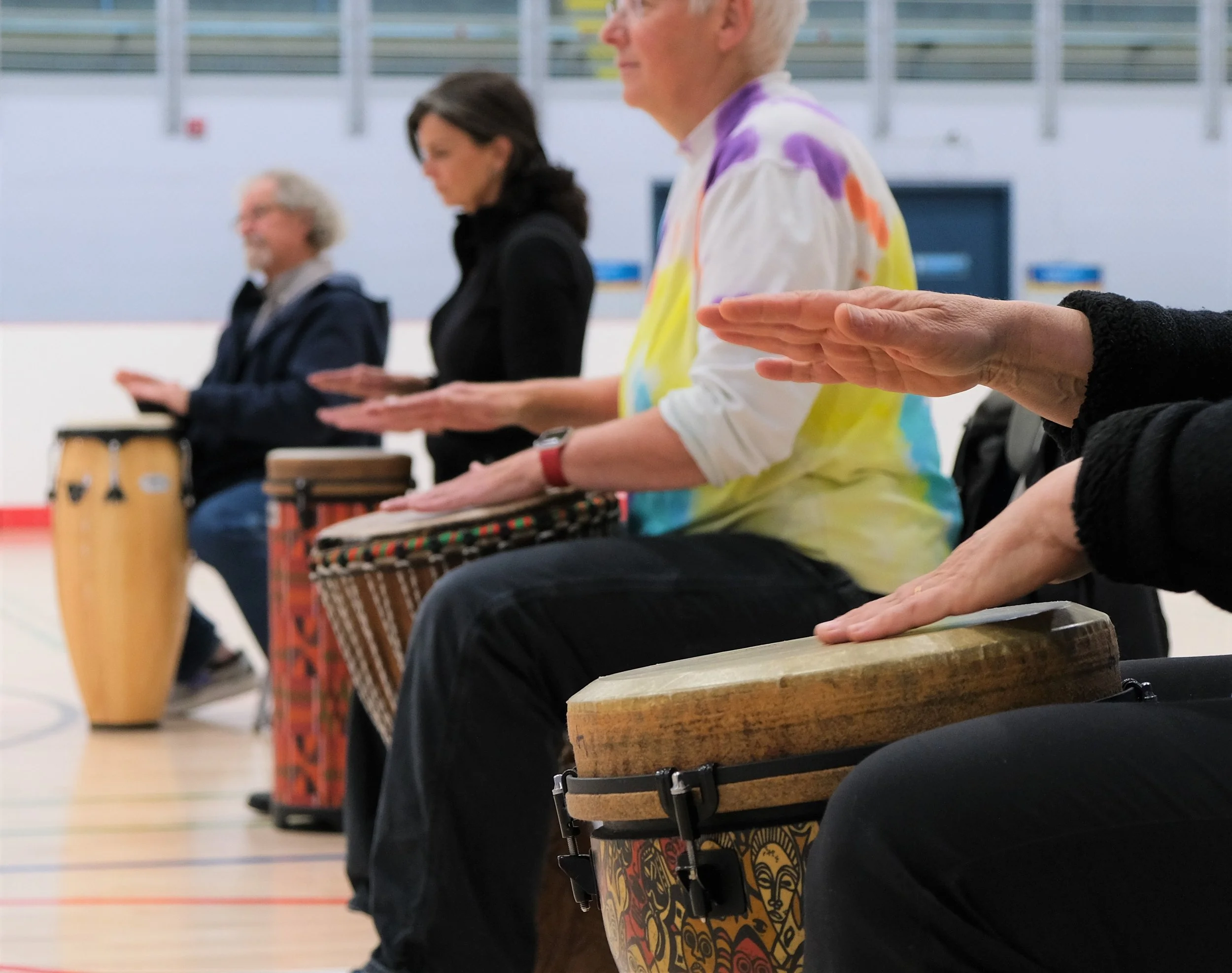 Several older adults drumming in a circle