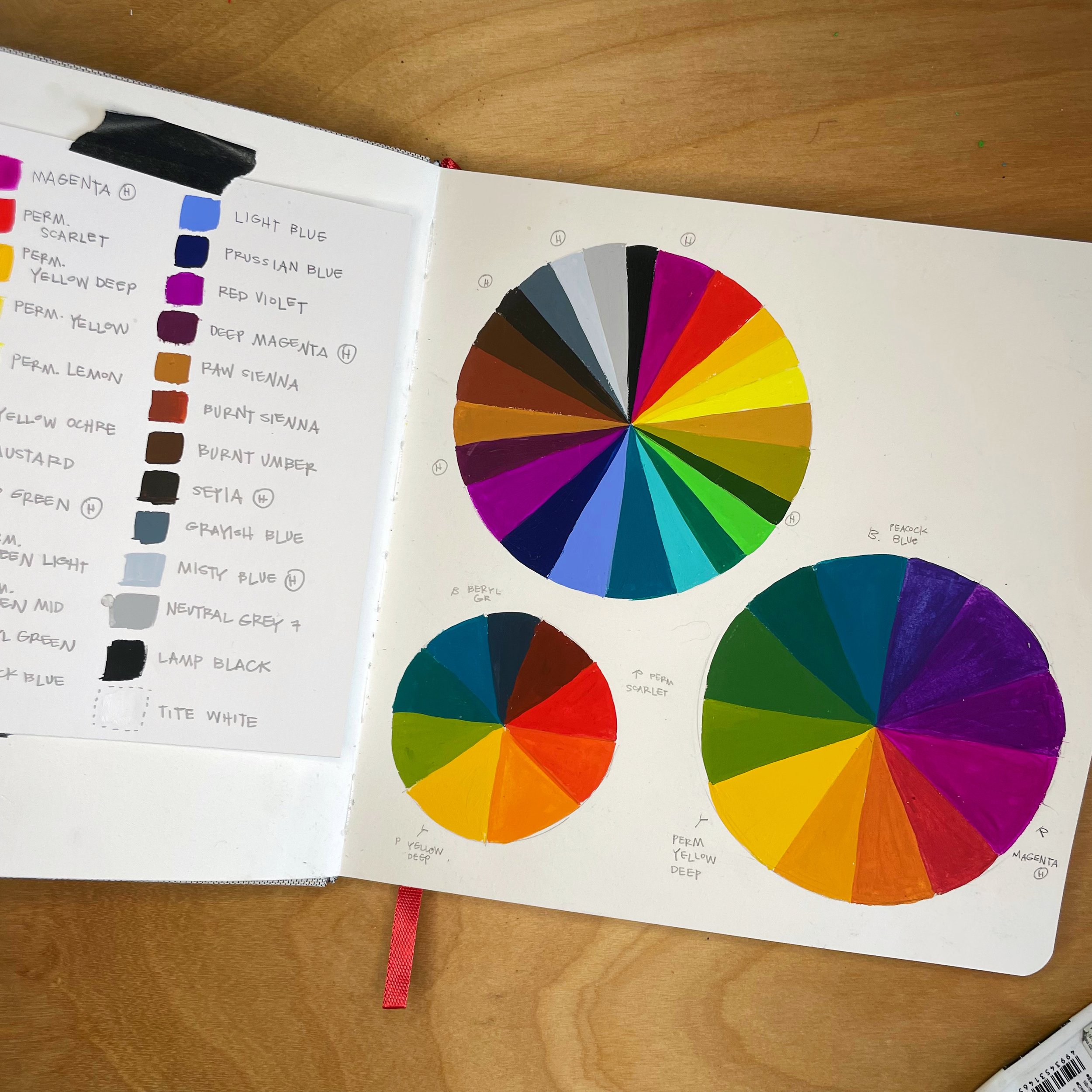 A sketchbook spread with color swatches on one page and three color wheels on the other page.