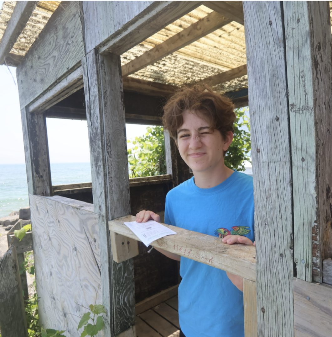 Intern Esme standing inside a wooden fort beside the beach