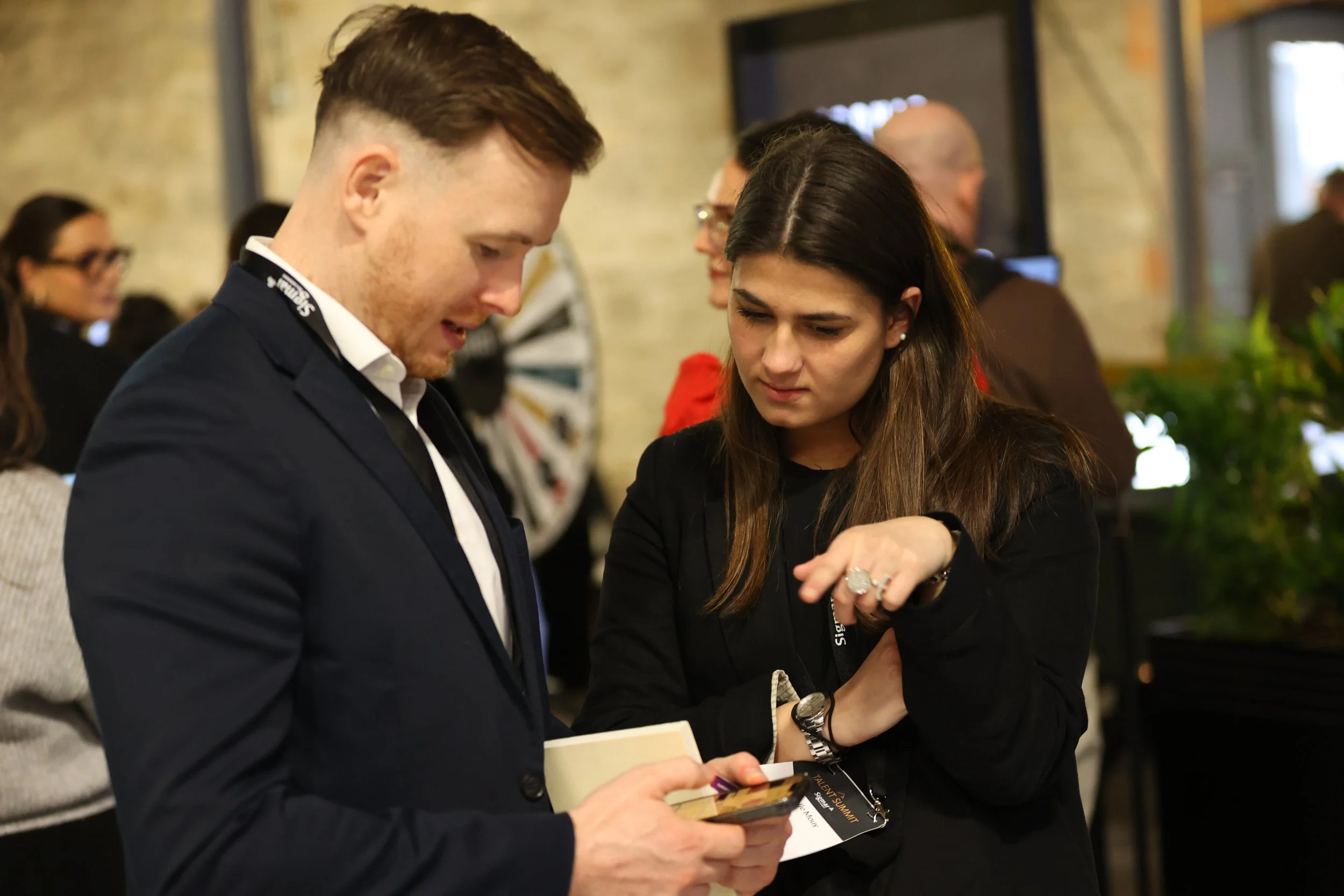 Two sigmar staff at Talent Summit Dublin use the Talent Summit app to check the agenda for the day.