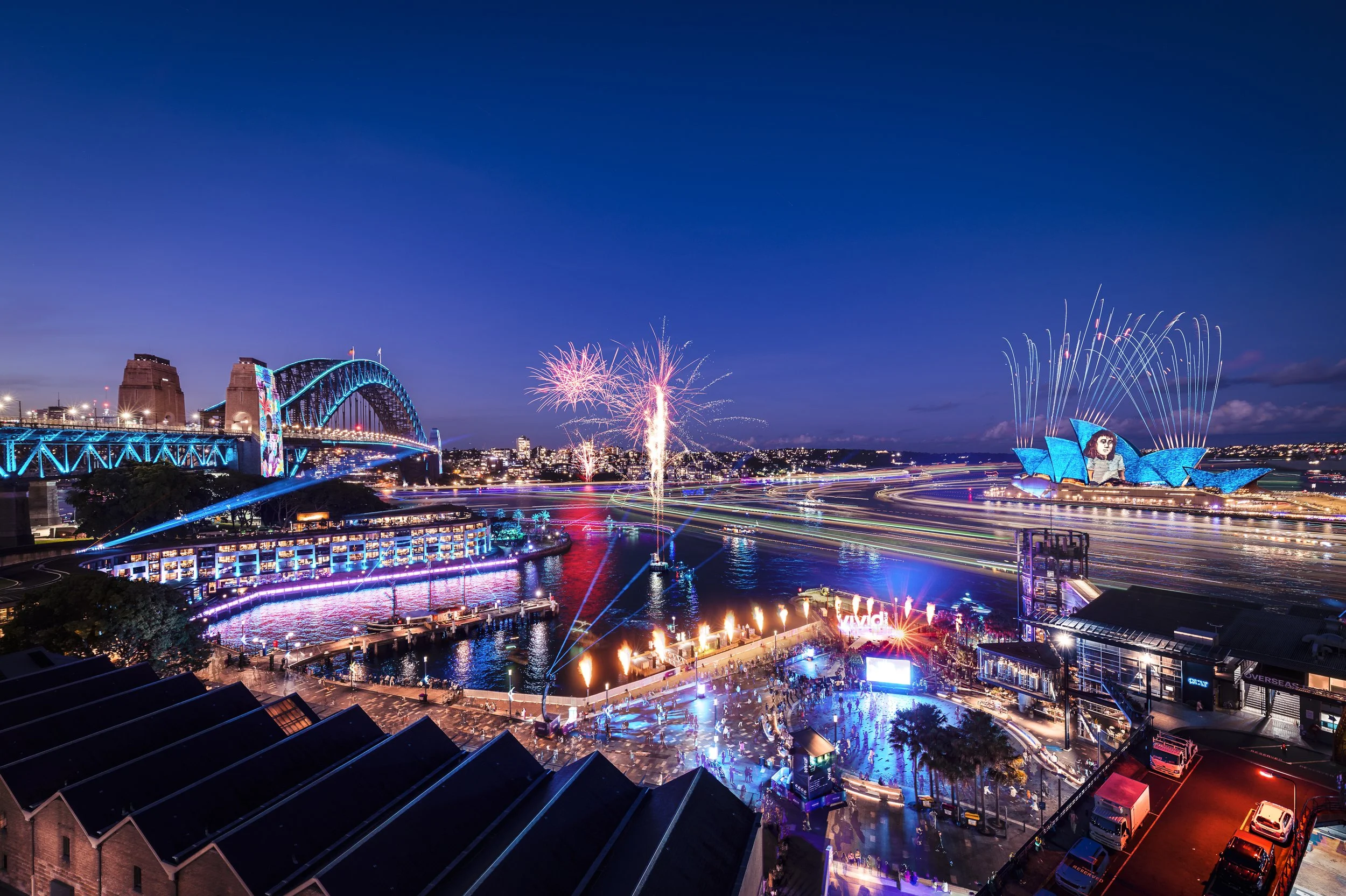 Night view of Sydney Harbour with fireworks display, Sydney Opera House illuminated, and Harbour Bridge lit up, celebrating the opening night of Vivid Sydney.