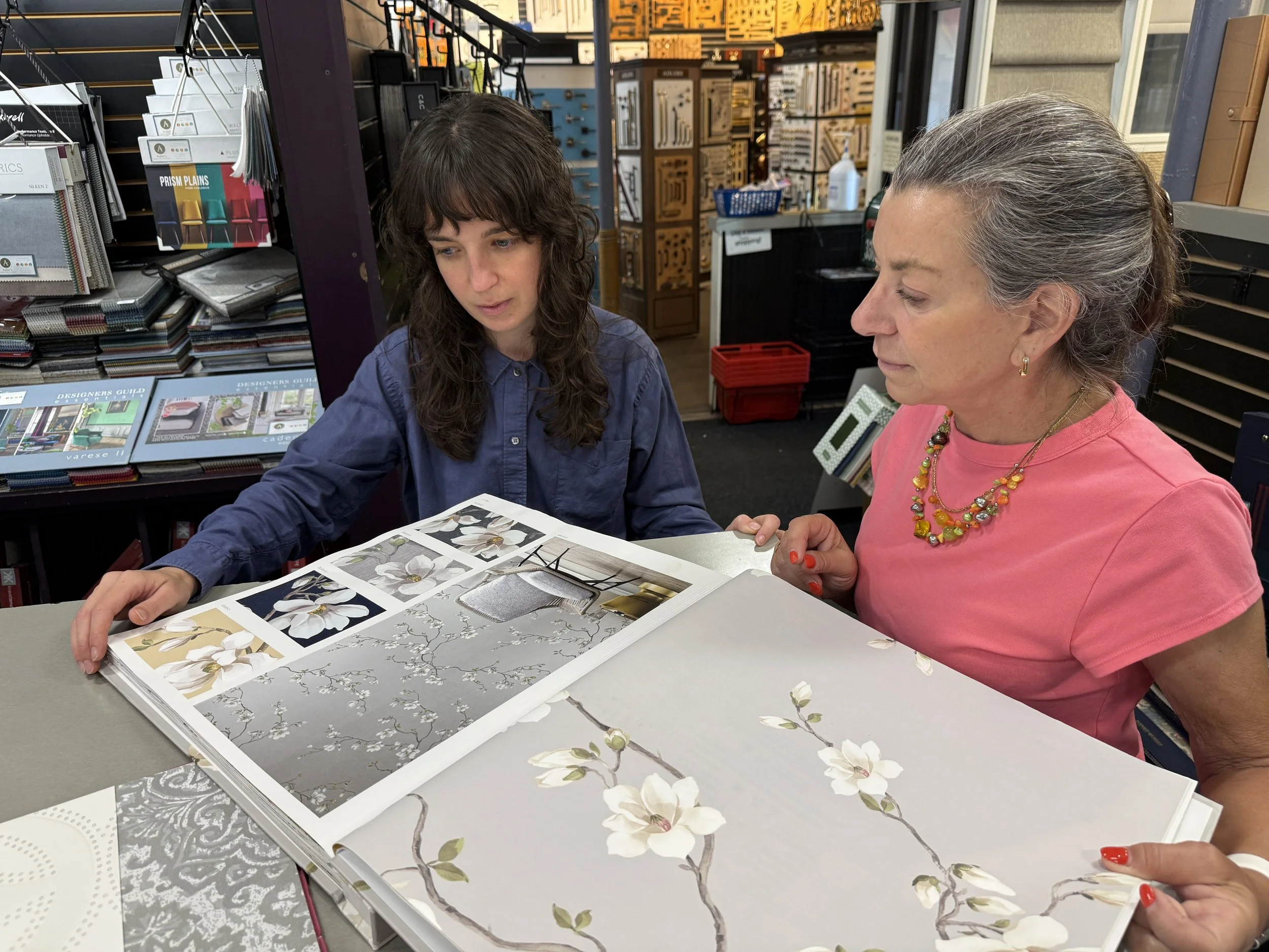 interior designer looking through wallpaper books with a customer