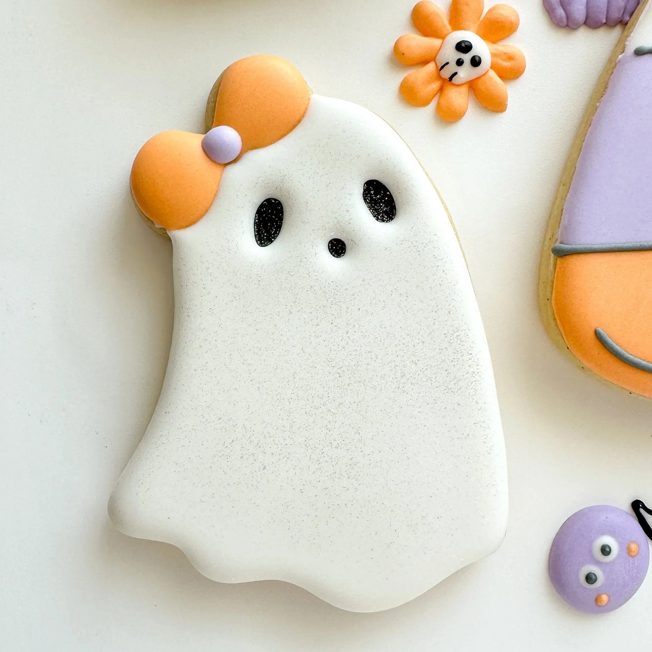 White ghost wearing orange bow decorated cookie