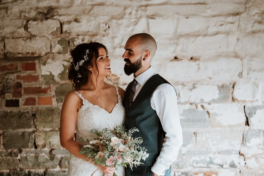 bride and groom posing for photos next to a brick wall