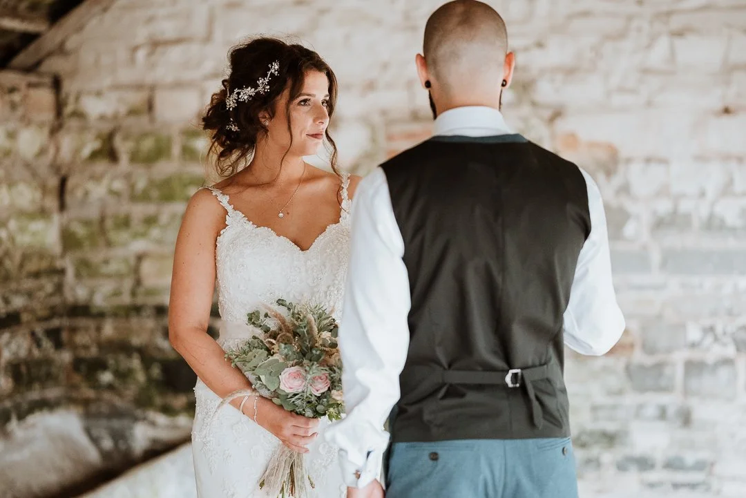 bride and groom posing for photos next to a brick wall