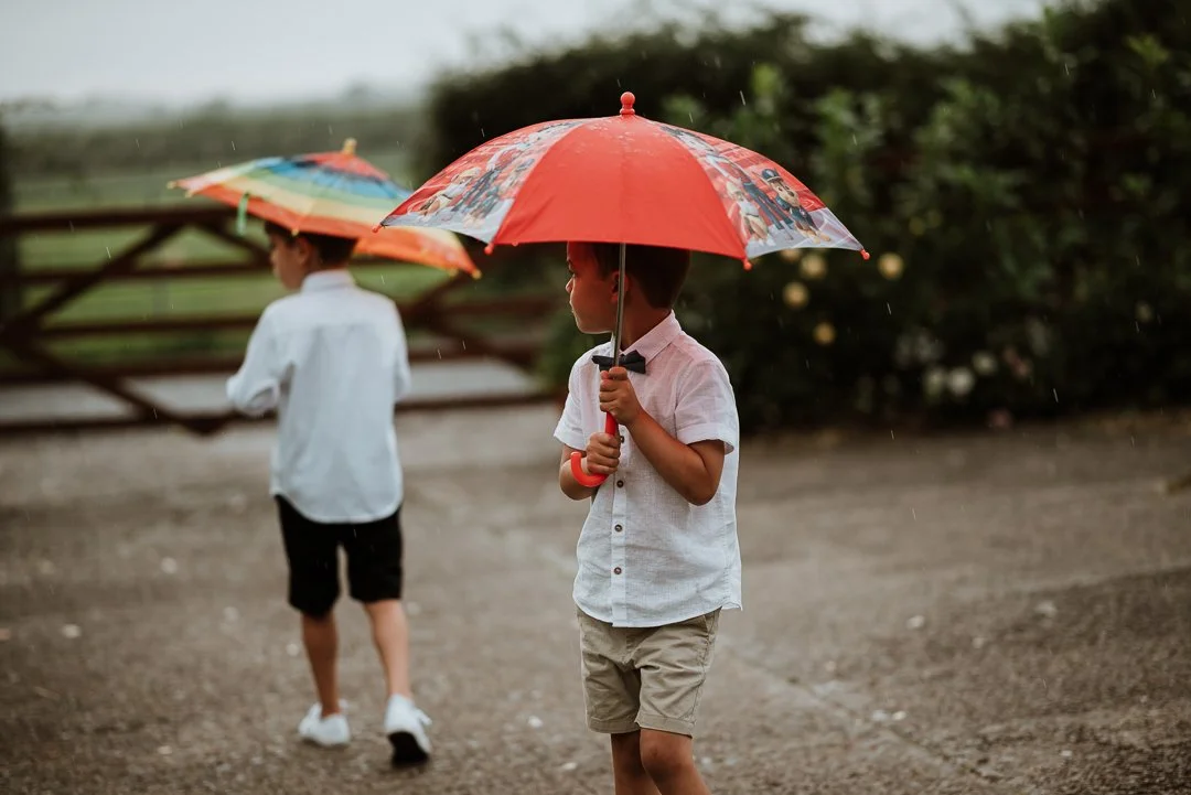 two young children holding an umbrella at a wedding