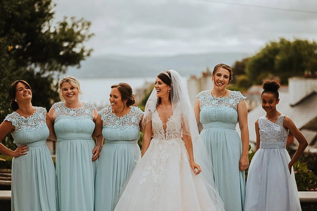 bride and her bridesmaids pose together for a pre-wedding photo looking at each other and laughing, in Bristol