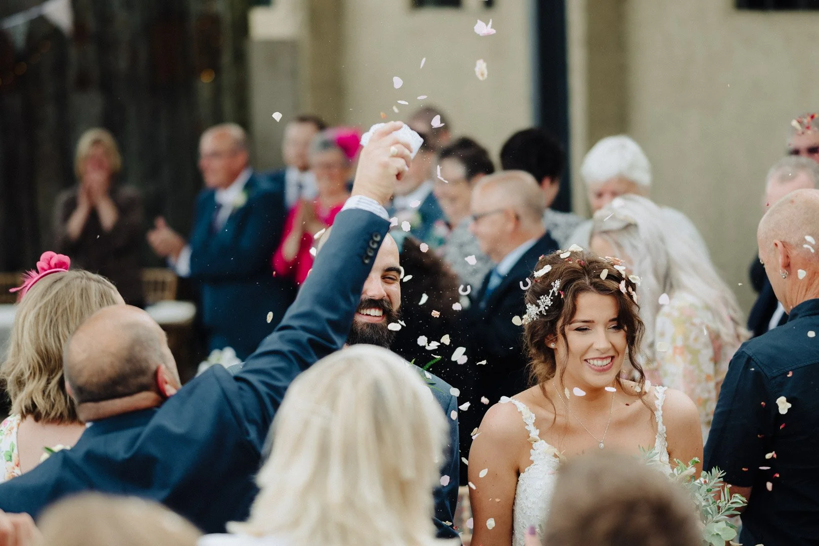 bride and groom have confetti thrown on them as they walk back up the aisle after their outdoor ceremony at the Dairy House Farm Barn Weddings