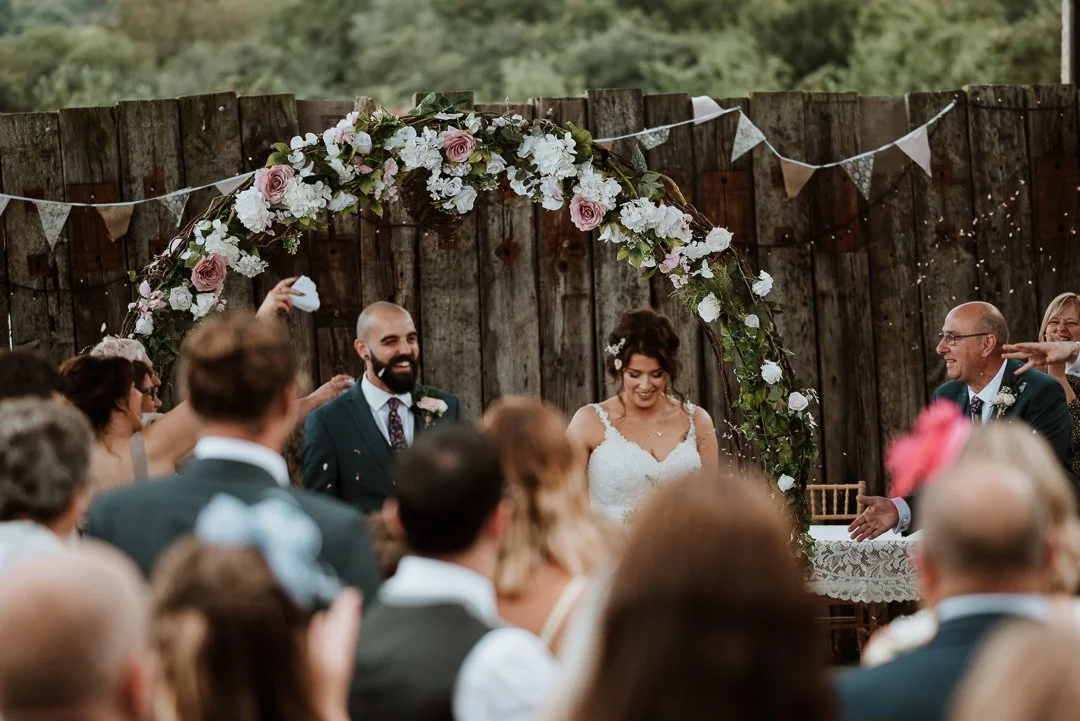 Bride and groom have confetti thrown over them after saying their vows