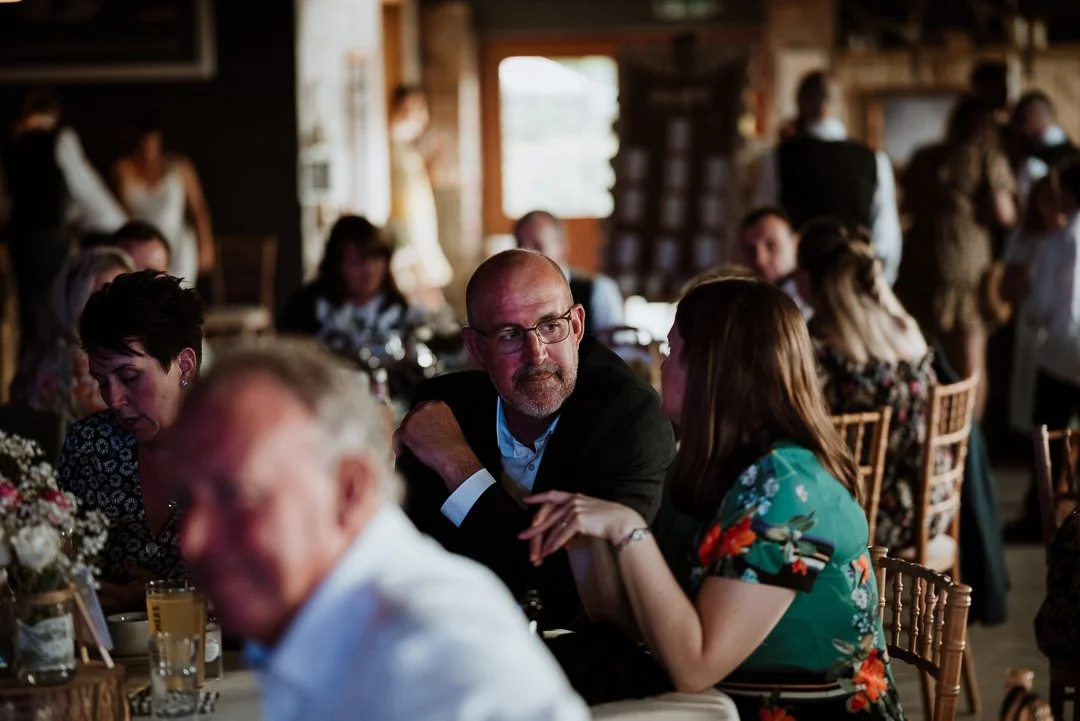 A man and lady sit at the wedding breakfast table having a conversation