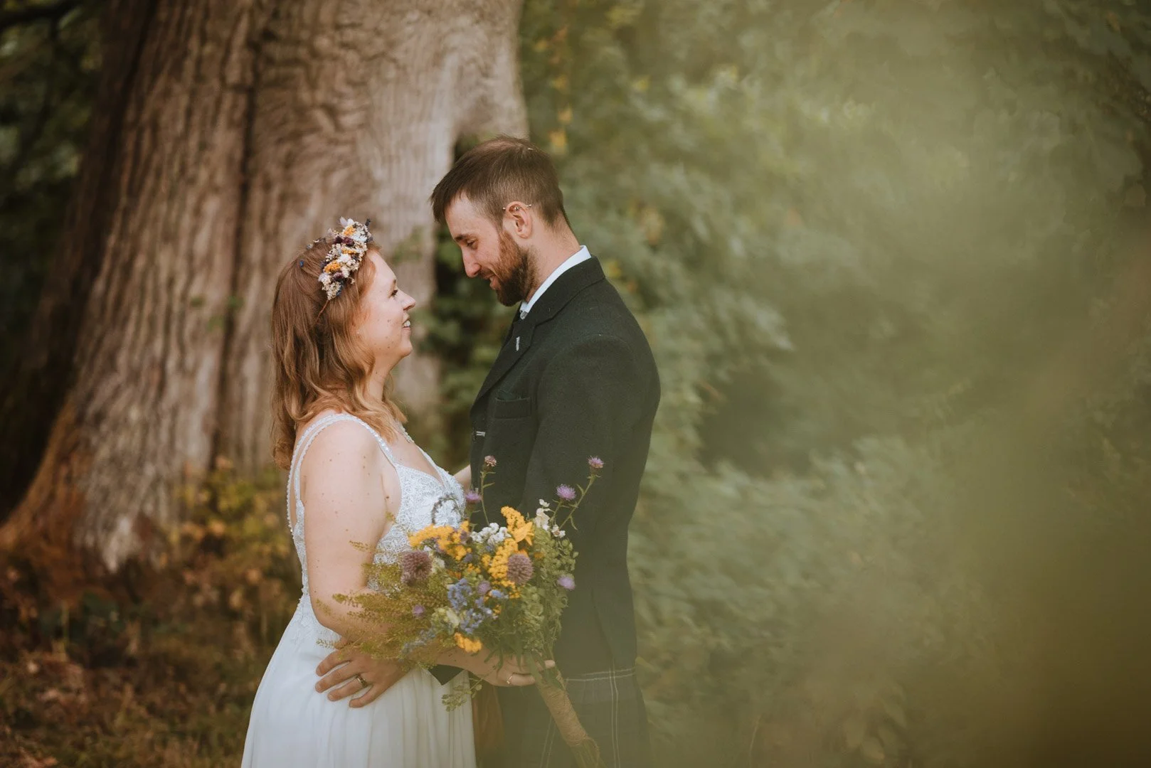A newly wed couple have a portrait in the woodlands of a camping site in Bath Somerset, staring lovingly at each other next to an oak tree
