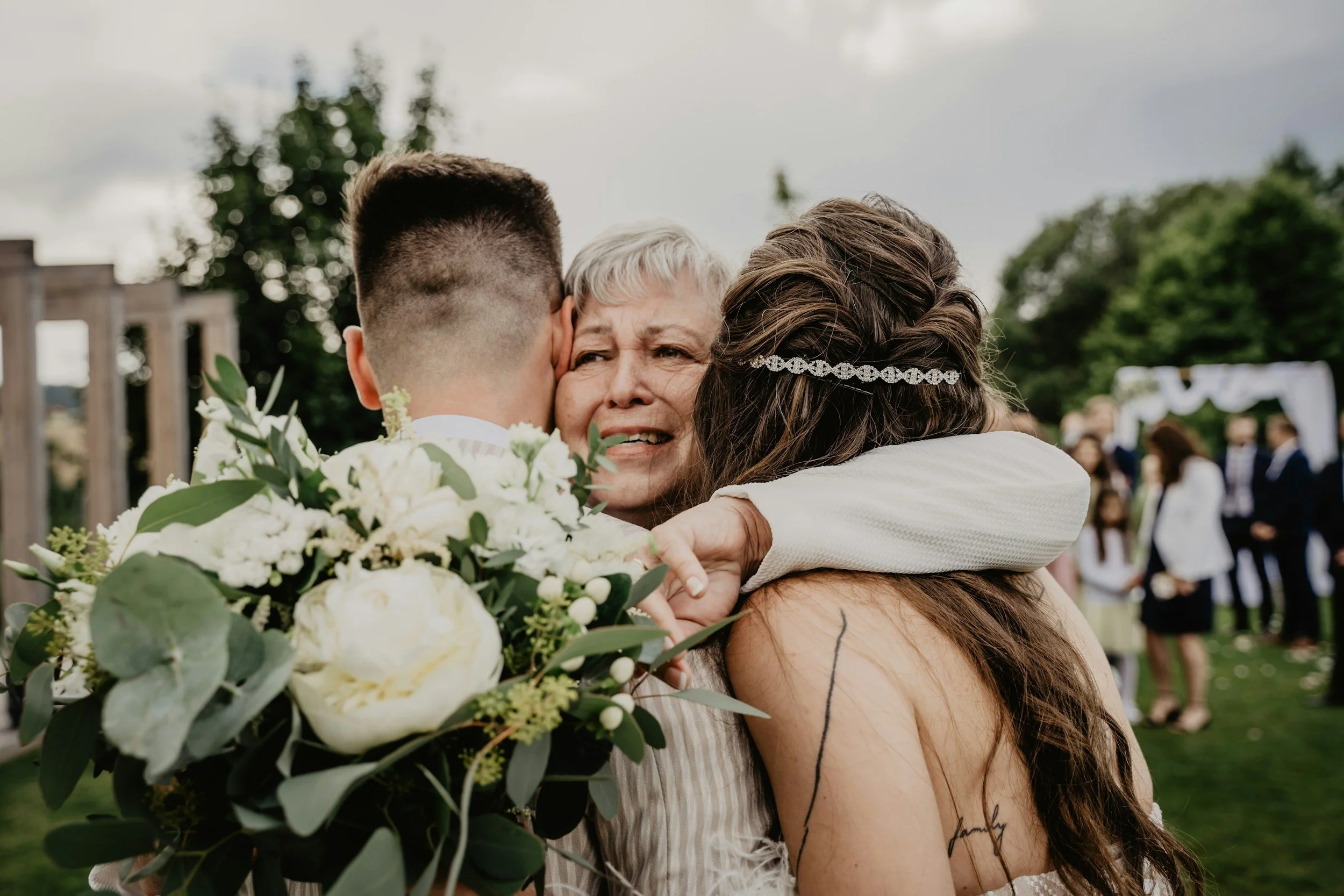 Mom sheds happy tears as she hugs newlywed bride and groom.