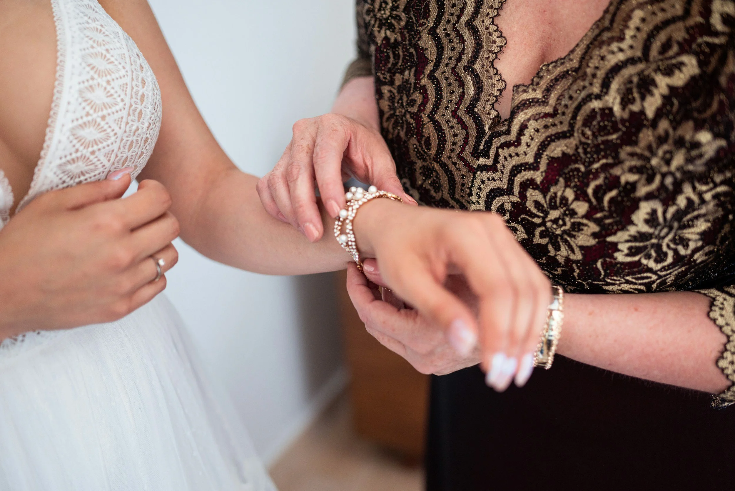 Mom and daughter wear matching bracelets at wedding.