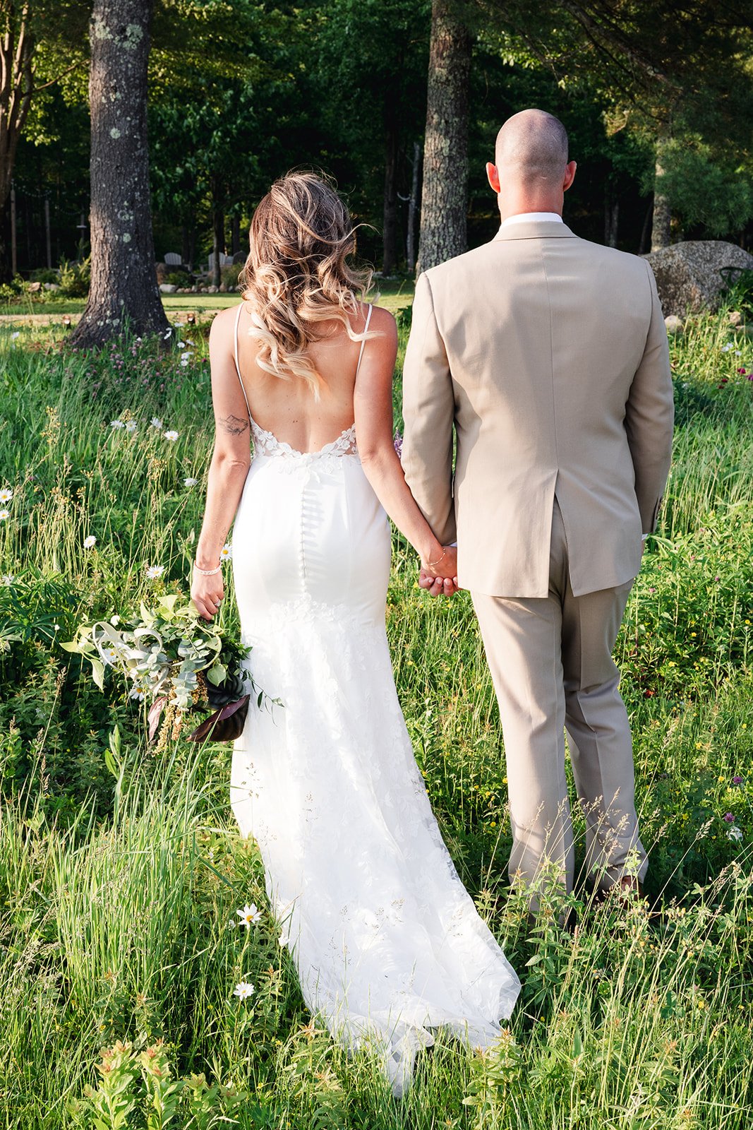 Bride and groom walk through the wildflower garden towards their reception.