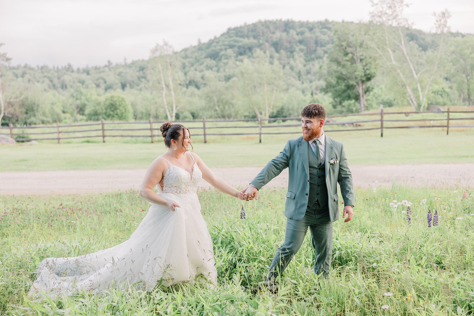 Bride and groom walk through a patch of wildflowers during their garden wedding.