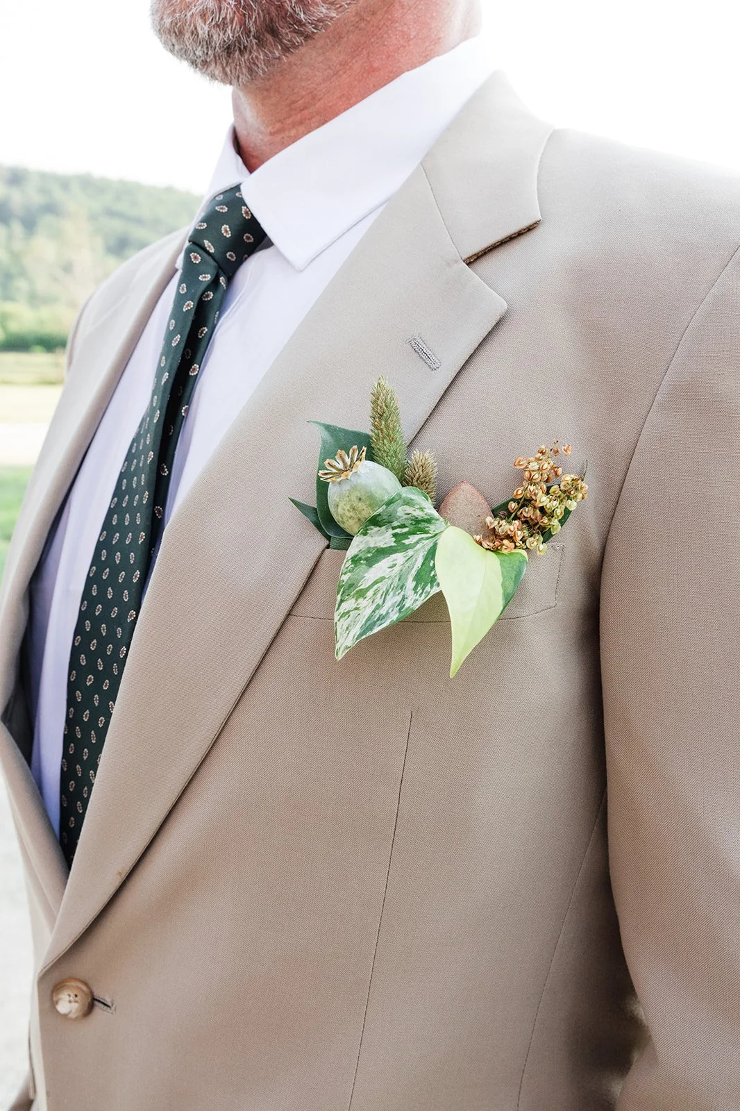 Groom shows off his pocket boutonnière made from greenery.