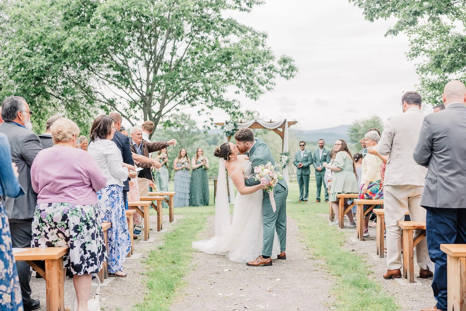 Newlyweds share a kiss on the aisle during their outdoor wedding ceremony.