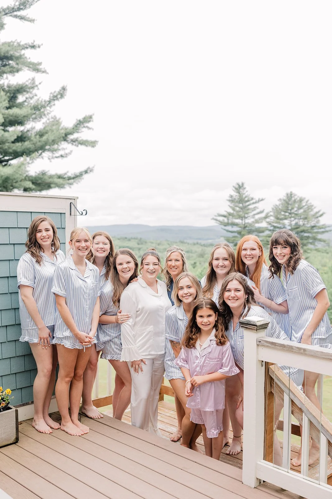 Bride and her bridesmaids pose on the deck with mountain views in matching pajamas while getting ready for the wedding.