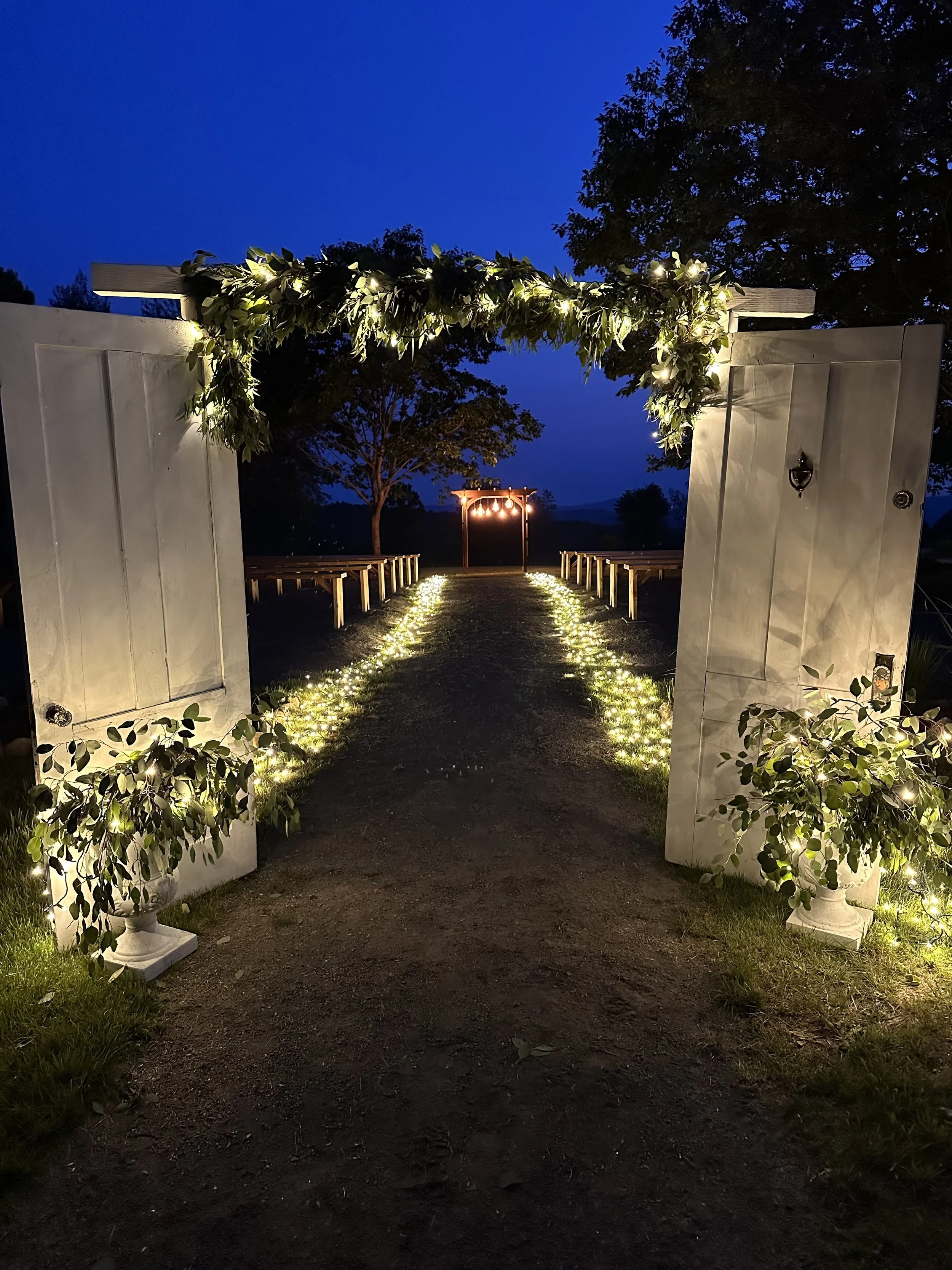 Outdoor ceremony area at night lit up with thoughtful wedding lighting design.