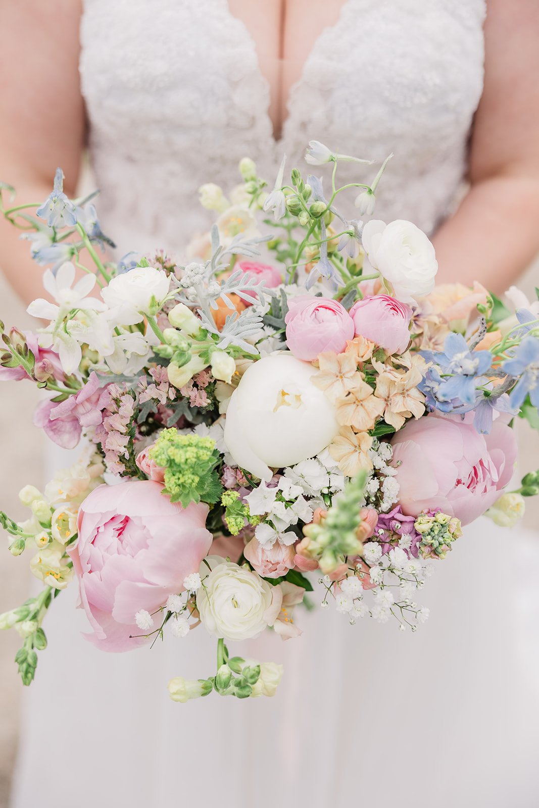 Close up shot of a bridal bouquet filled with pink, green, blue, and white flowers at garden wedding ceremony.