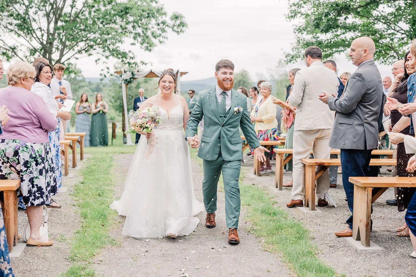 Bride and groom smile as they recess back down the aisle after their garden wedding ceremony.