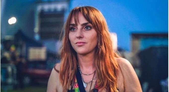Close up picture of Harry Jones. A white female with gold/copper hair wearing a festival lanyard.