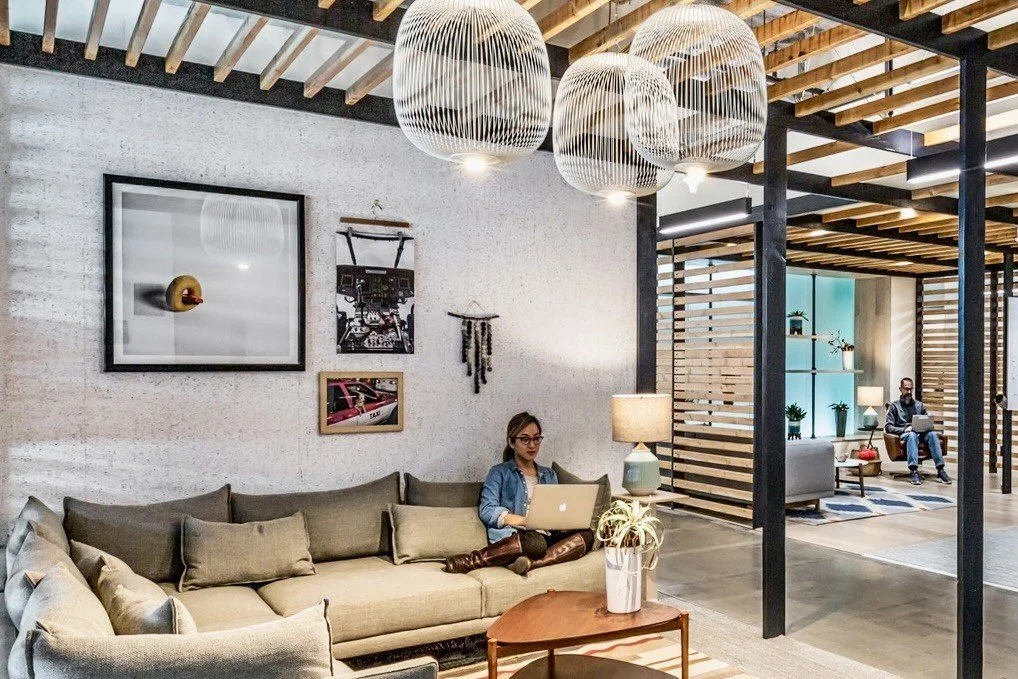 Artworks displayed in a contemporary workplace lounge with seating and shared work areas.