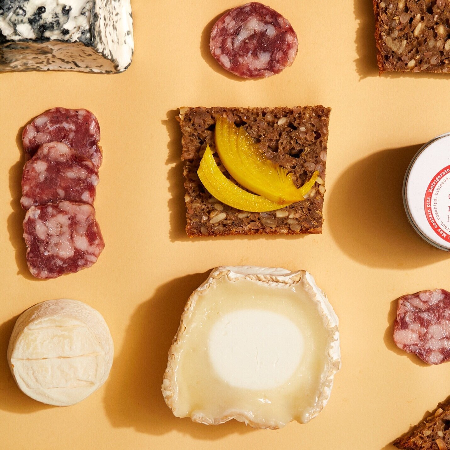 Cheeses, toast, and meets laid out on yellow paper.