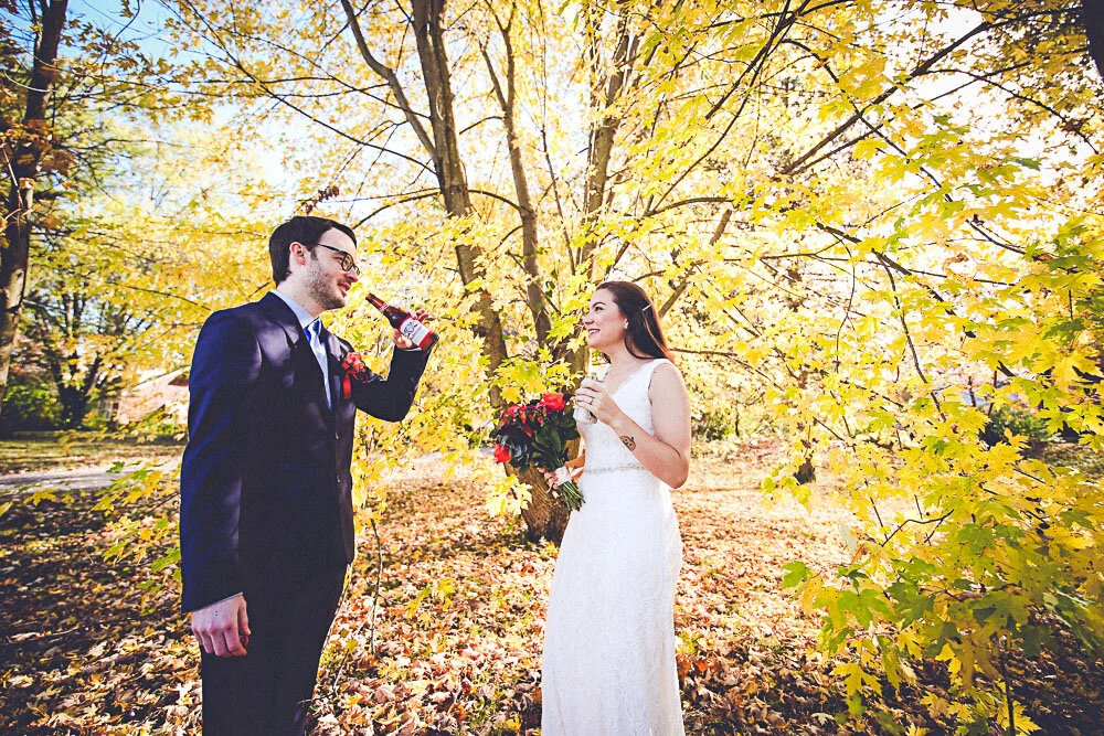 A large tree full of yellow flowers is the perfect backdrop for a wedding couple to share a quick moment and beer together in the fall.