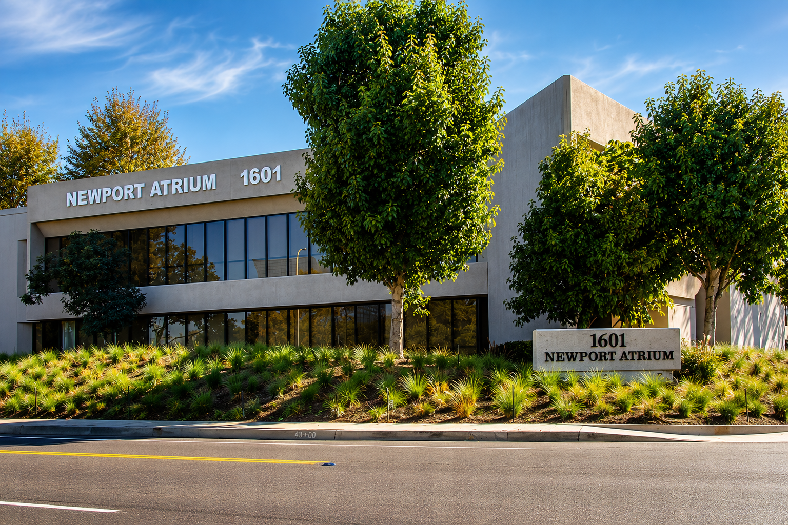 Exterior of the Newport Atrium building at 1601 with trees, greenery, and a clear blue sky.