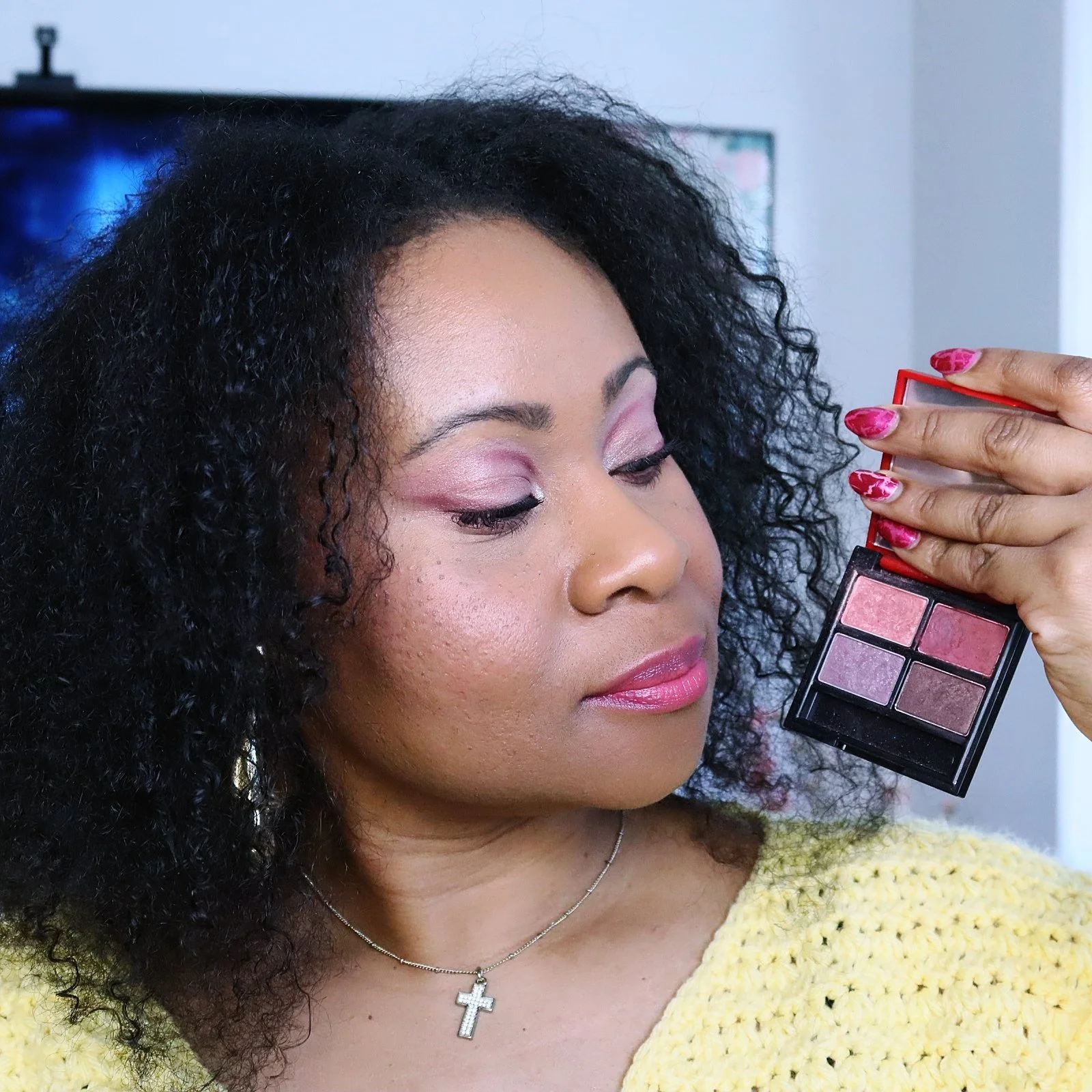 balck woman with natural hair holding eyeshadow palette