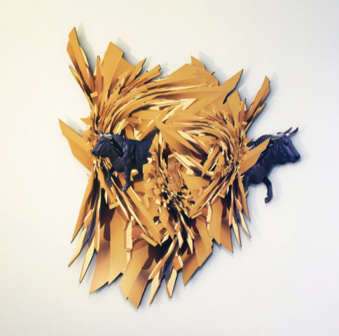 A three-dimensional paper sculpture of a lion's head with a tan mane and two black panthers attached.