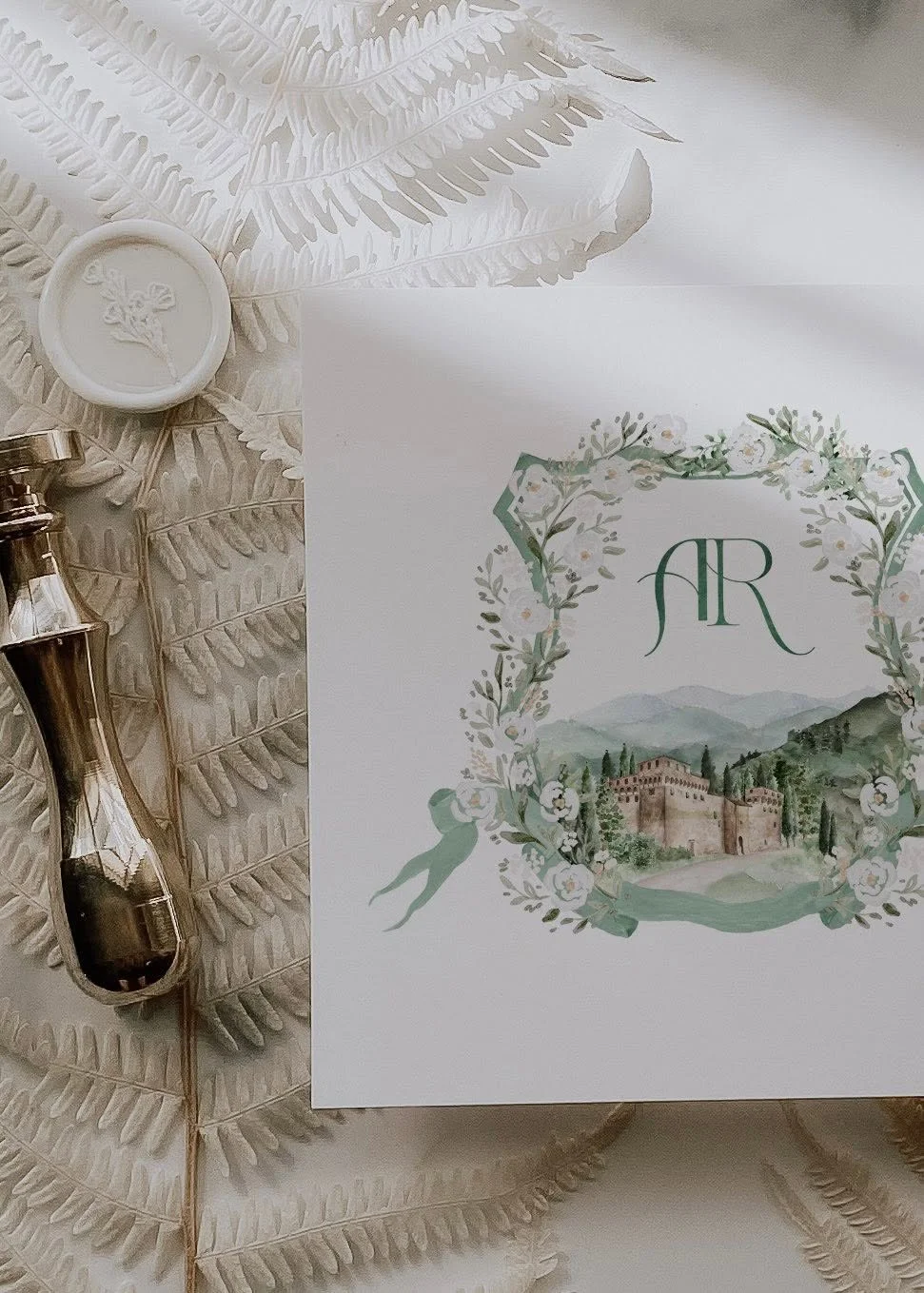 Hand-painted custom wedding crest with floral monogram and illustrated Tuscan villa created for a luxury destination wedding invitation suite.