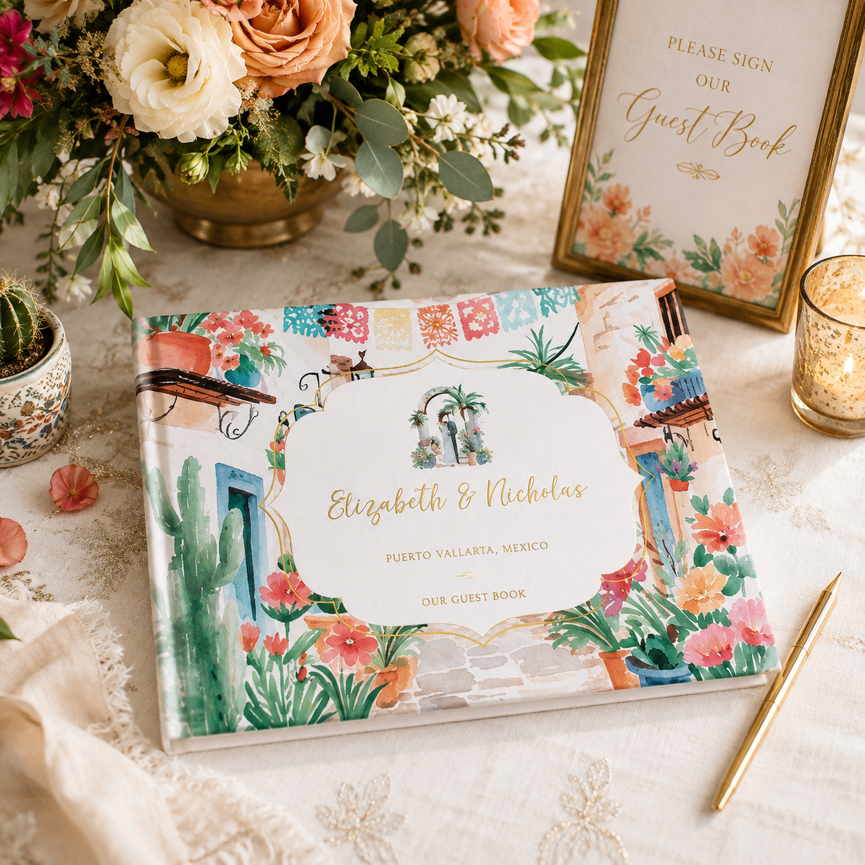 Styled mockup of a watercolor Puerto Vallarta wedding guest book with real gold foil details, displayed alongside elegant florals, a guest book sign, candle, and gold pen.