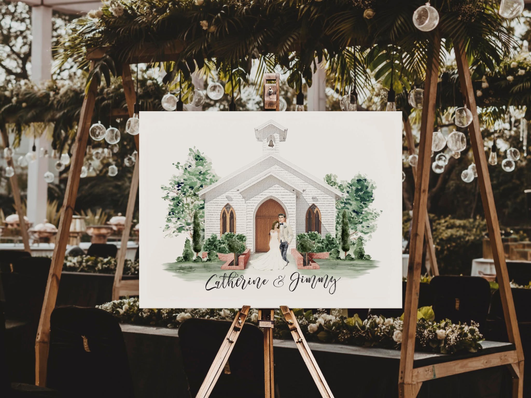 Large wedding welcome sign featuring a custom watercolor illustration of the bride and groom standing in front of their ceremony chapel, displayed on an easel beneath a lush floral ceremony arbor.