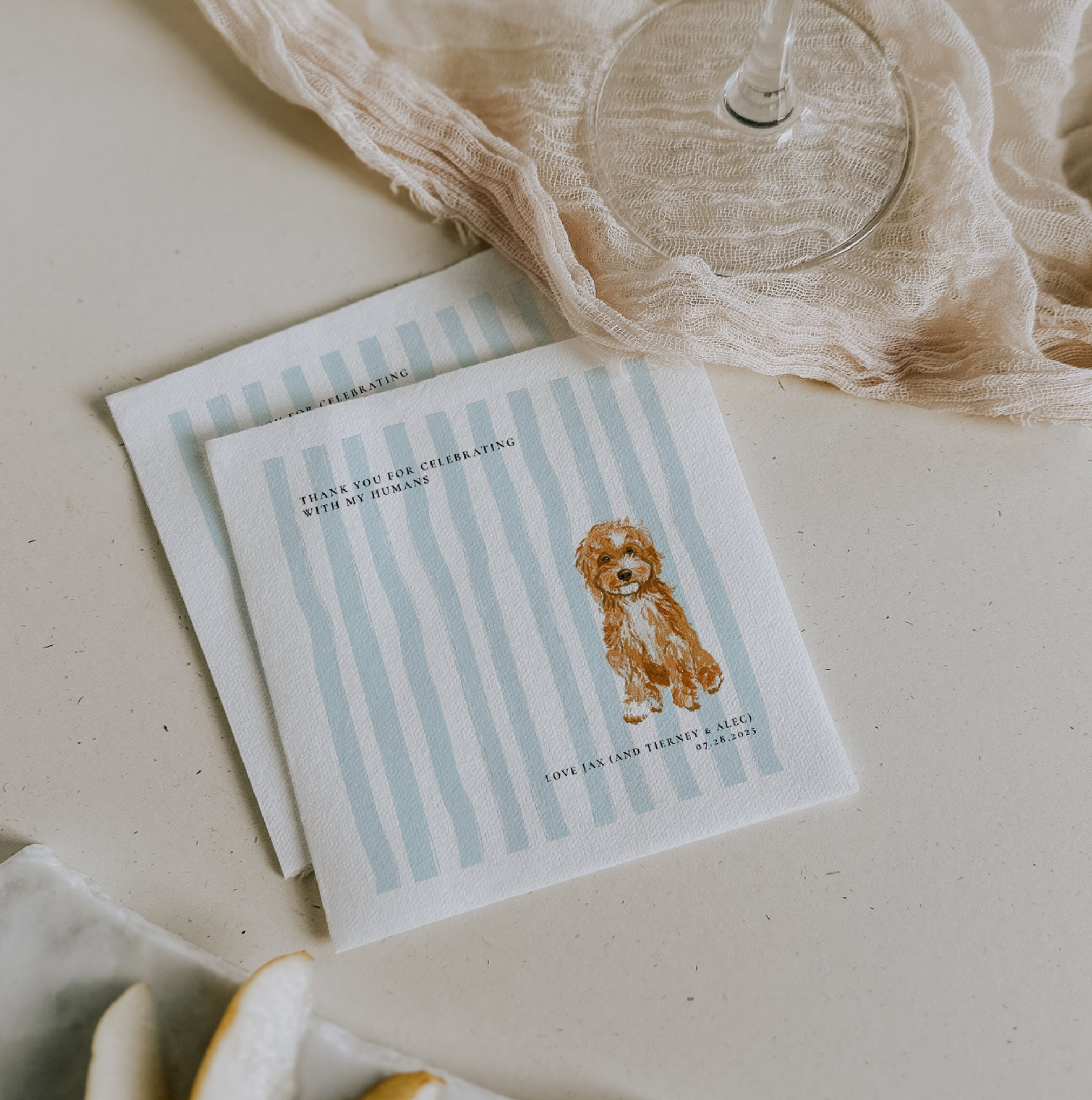 Personalized wedding cocktail napkins featuring a custom watercolor illustration of the couple's dog on soft blue stripes, paired with a playful message thanking guests for celebrating with the couple's beloved pet.