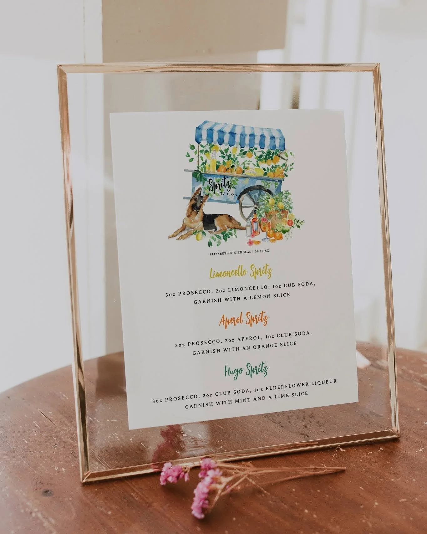 Wedding spritz station menu featuring a custom watercolor illustration of a lemon spritz cart and the couple's German Shepherd, displayed in a modern gold floating frame as personalized wedding bar signage.