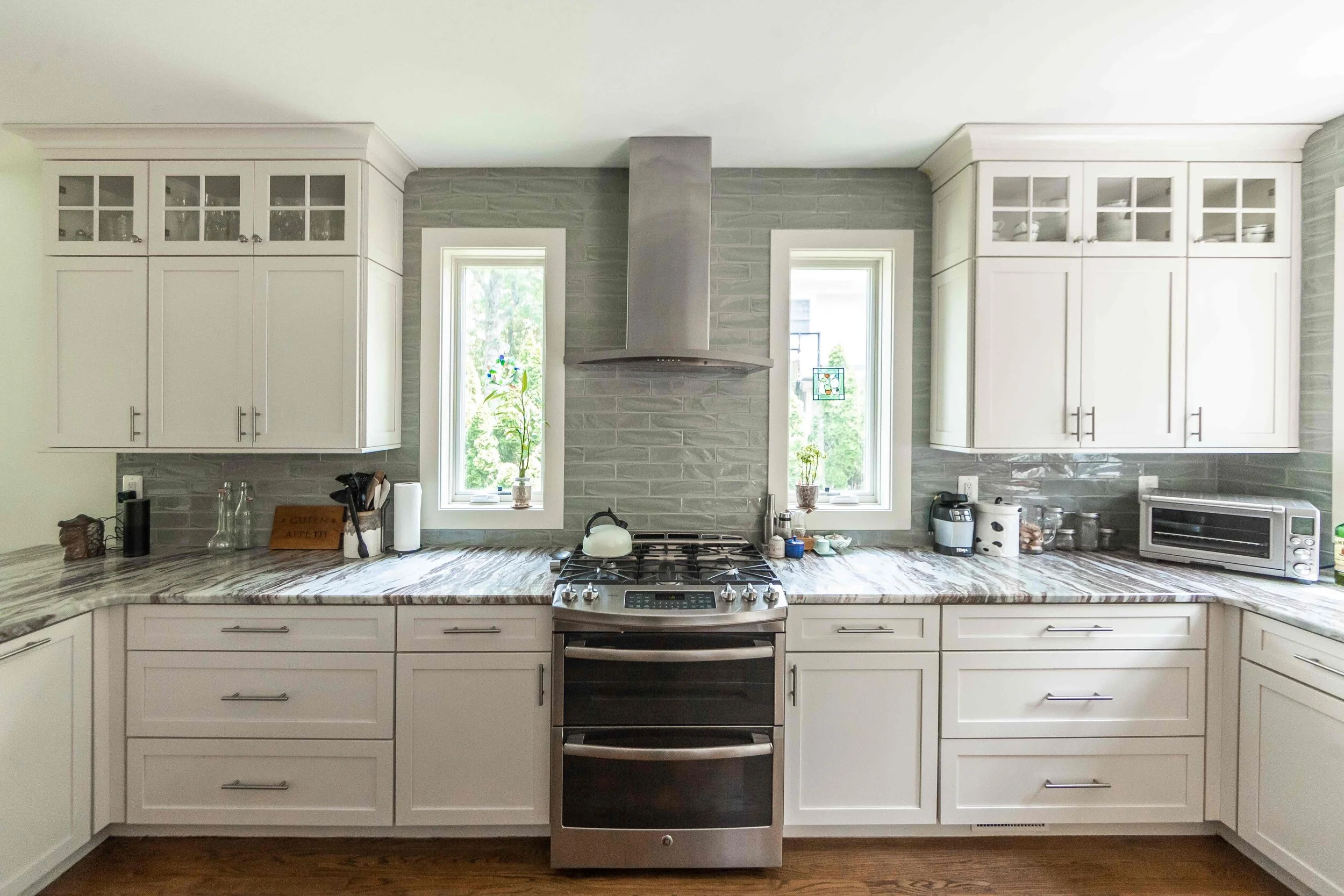Modern kitchen with white cabinets, stainless steel appliances, and gray backsplash