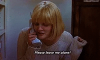 Une femme blonde parle au téléphone, l'air triste, en portant un pull gris. Il y a un sous-titre en anglais qui dit 'Please leave me alone!'.